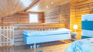A cozy cabin bedroom with a wooden ceiling, a bed, a nightstand, and a window.