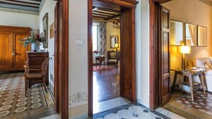 Un corridoio con porte in legno, un pavimento decorato e vista su una sala da pranzo con tavolo e sedie.