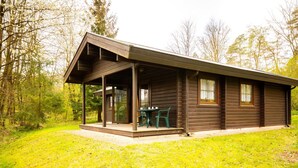 A wooden cabin with a covered porch and a table with chairs. - Vacation home Geli by Interhome (Bad Arolsen)