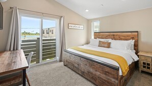 Une chambre à coucher avec un lit en bois, un bureau et une vue sur l’extérieur grâce à une porte coulissante.