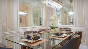 Un coin repas avec une table en verre, des chaises et un lustre.