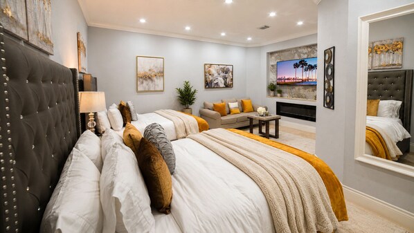Un dormitorio con una cama grande, un sofá, un televisor y una chimenea.