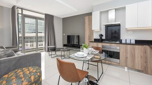 Een modern appartement met een eethoek, keuken en een groot raam met uitzicht op de stad.