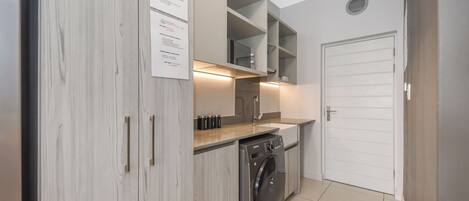 Cocina compacta con lavadora, estantes empotrados y una puerta blanca.