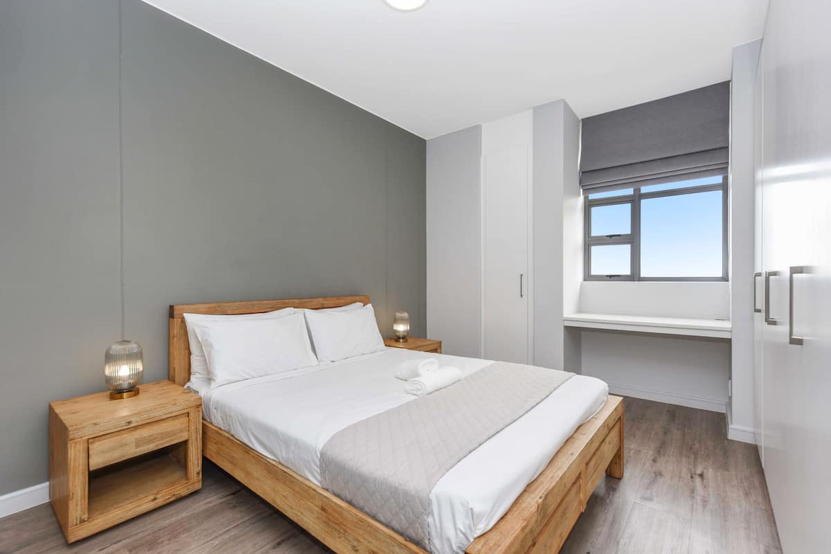 A bedroom with a wooden bed, bedside tables, a window with a view, and a wardrobe.
