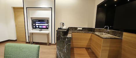 Una cucina moderna con TV integrata, macchina del caffè e lavello.