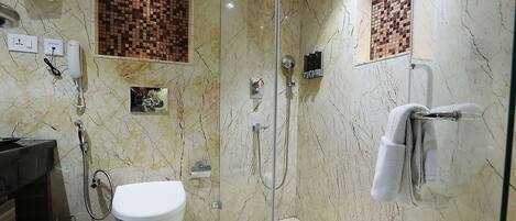 A modern bathroom with a glass-enclosed shower, a toilet, and a towel rack.