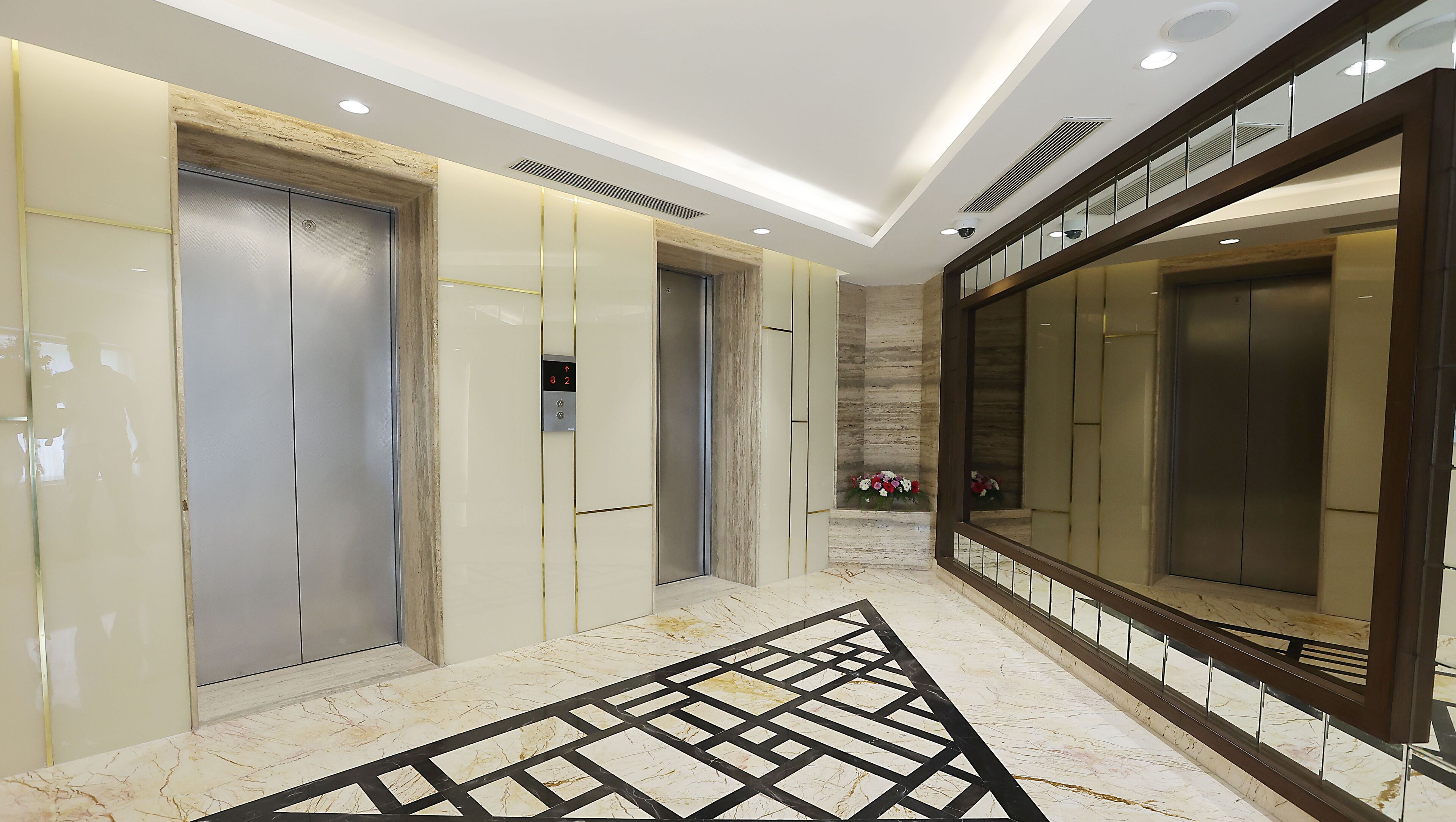 A modern elevator area with marble flooring and metallic elevator doors.
