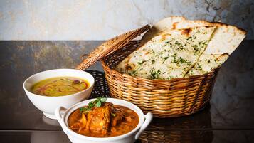 A dining table with two bowls of soup and a basket of flatbread.