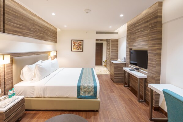 Una habitación de hotel moderna con una cama grande, mesitas de noche, un televisor y un escritorio.
