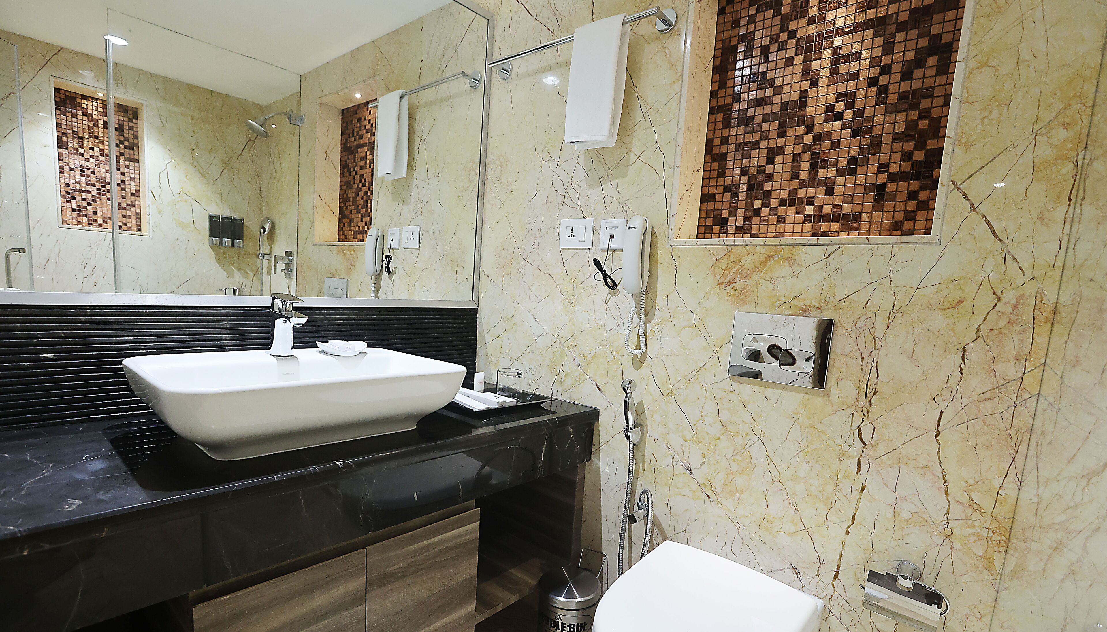 A modern bathroom with a large mirror, a white sink, and a black countertop.