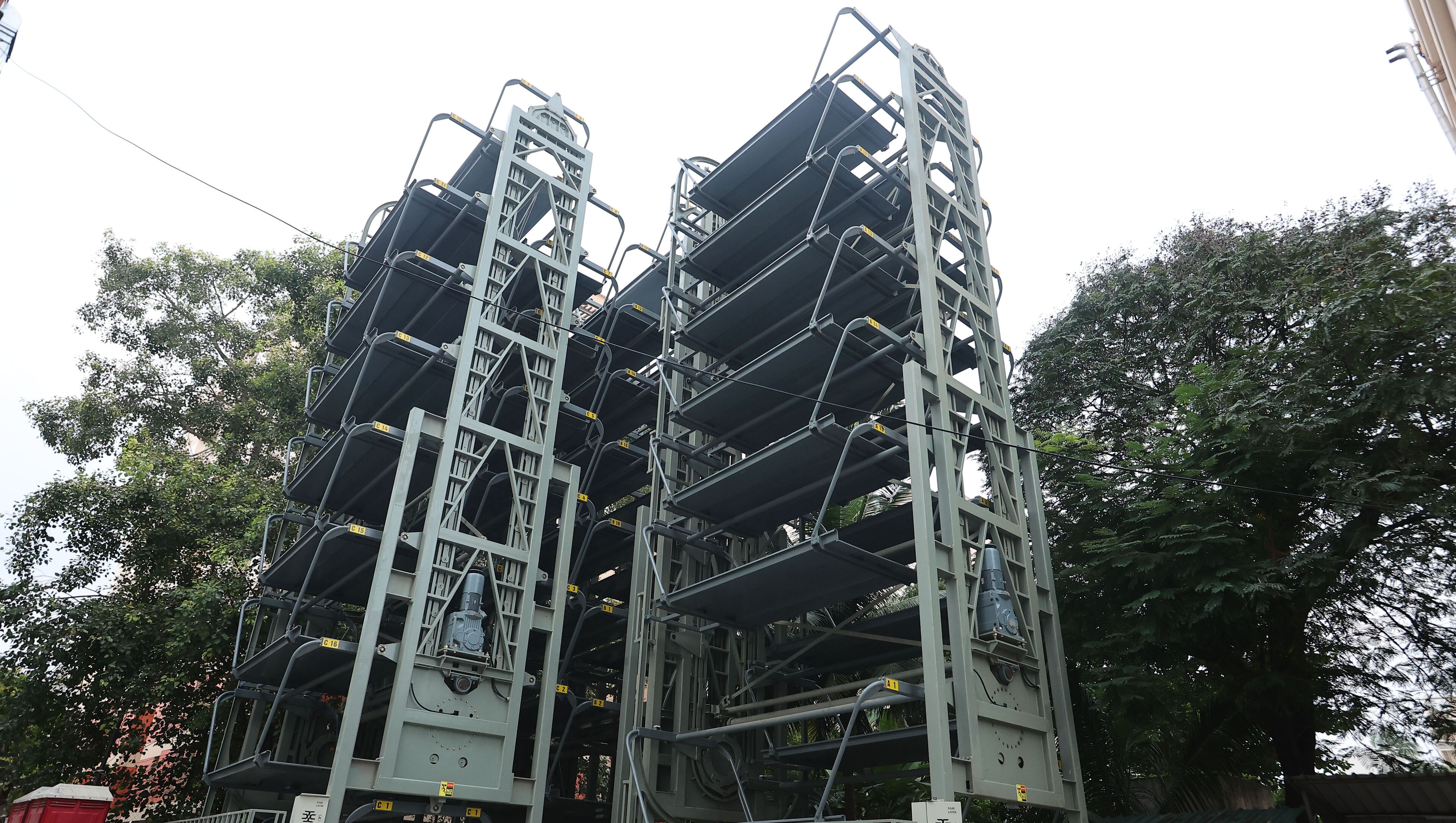 Una gran estructura industrial con varios niveles y barandillas de metal, rodeada de árboles.