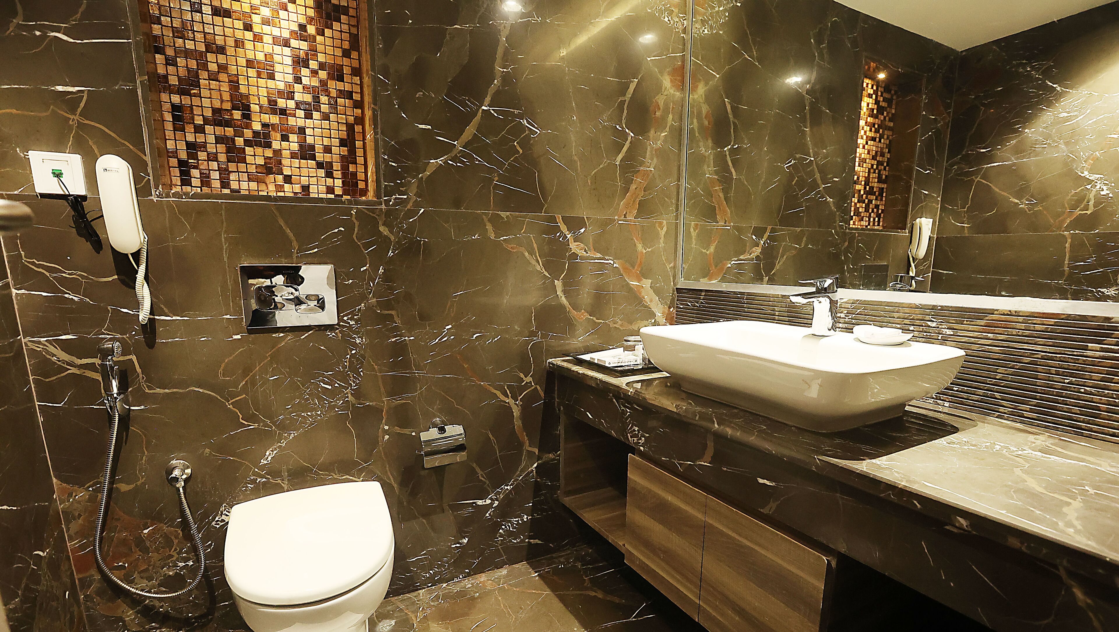 Un baño moderno con lavamanos de mármol, inodoro y ducha.
