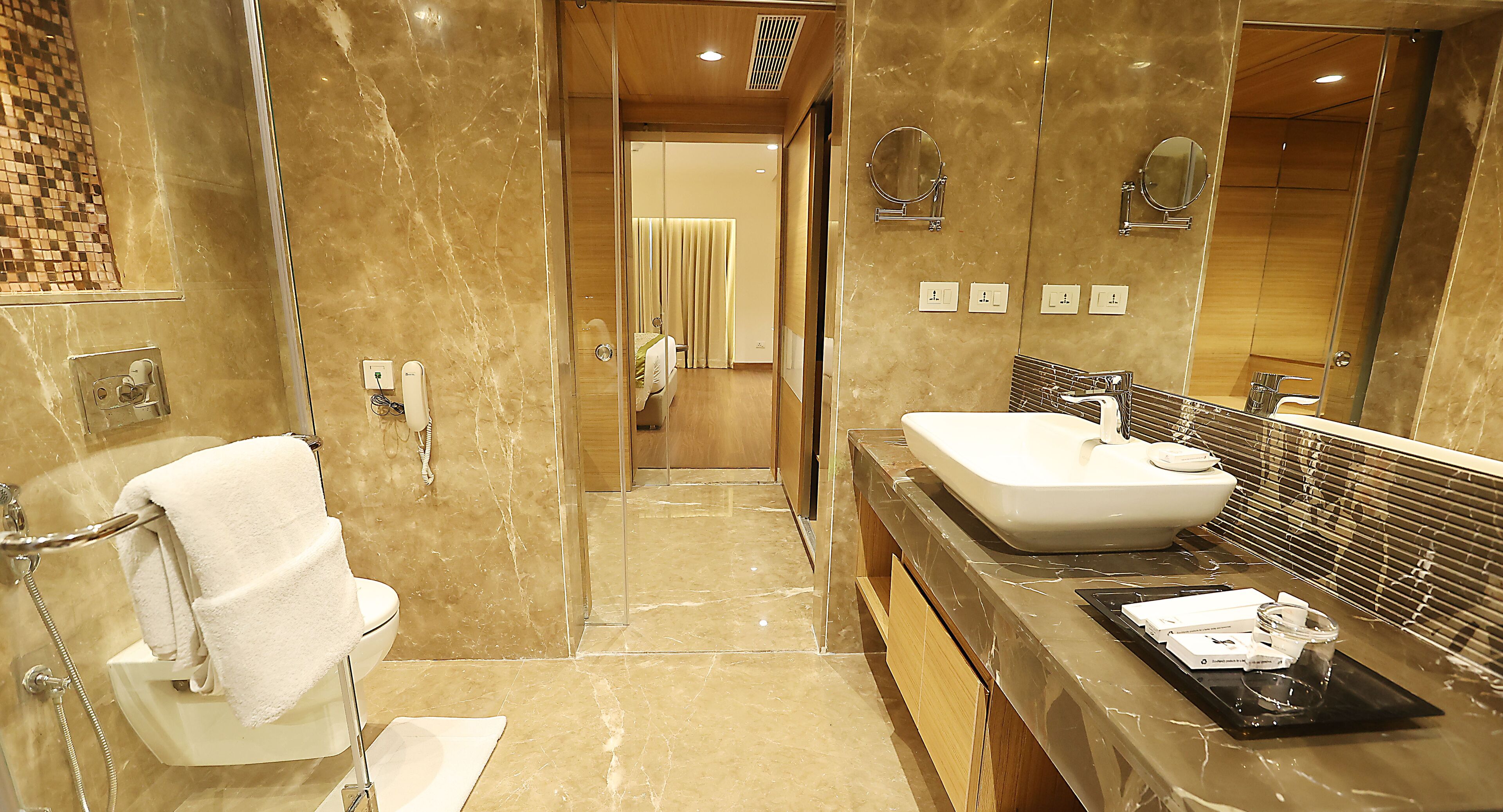 A modern bathroom with a marble floor, a white sink, and a glass shower enclosure.