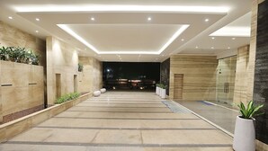 A modern hotel lobby with a spacious corridor, recessed lighting, and potted plants. - Pharos Hotels (Chennai)