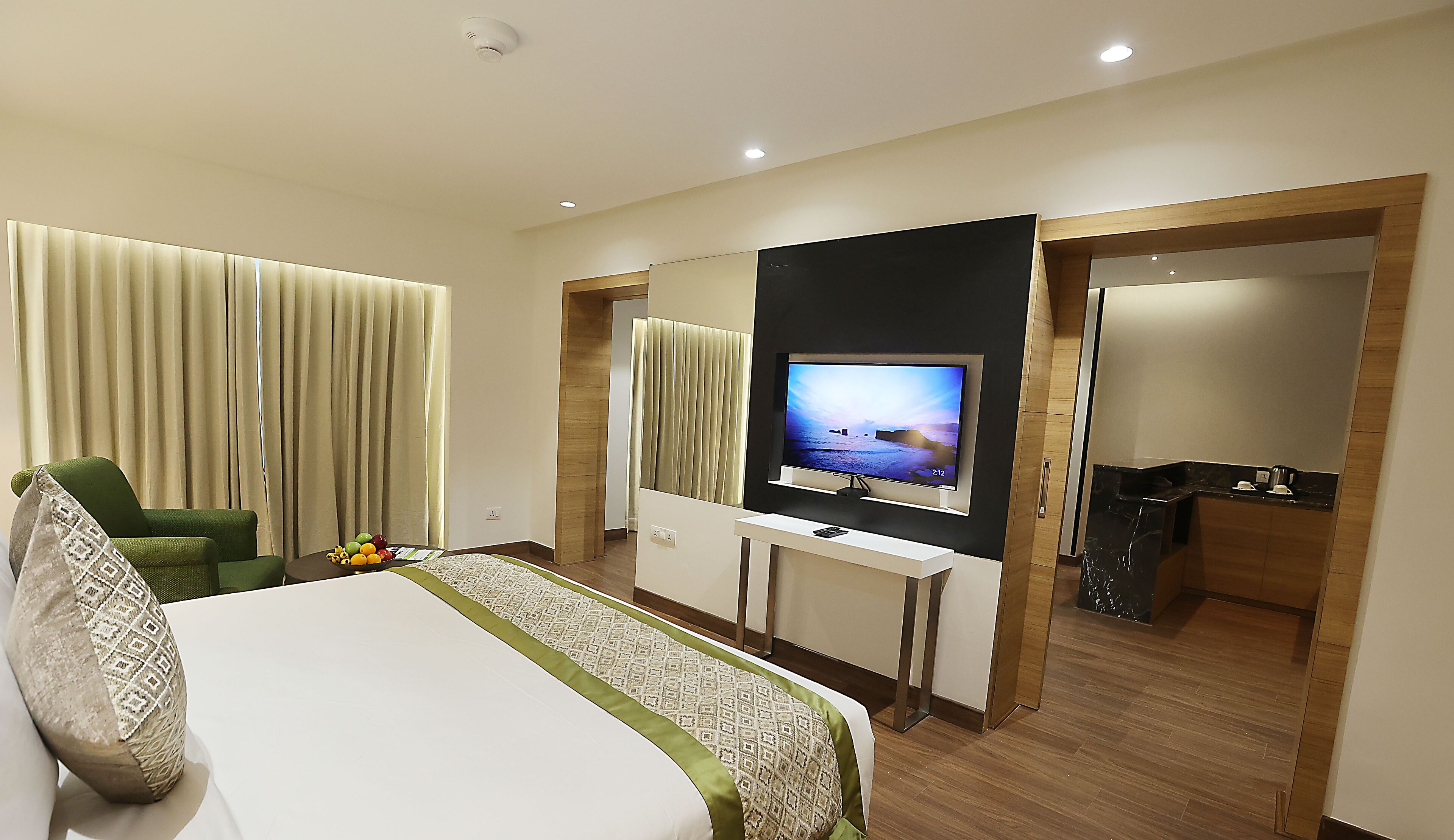 Ein Hotelzimmer mit Bett, Wandfernseher, Schreibtisch und Stuhl.
