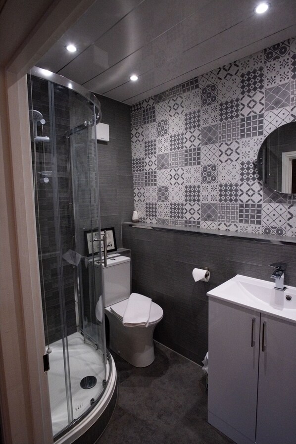 A modern bathroom with a glass-enclosed shower, a toilet, and a sink with cabinets. - LABURNUM HOUSE & BISTRO EN GLAZE (Wylam)