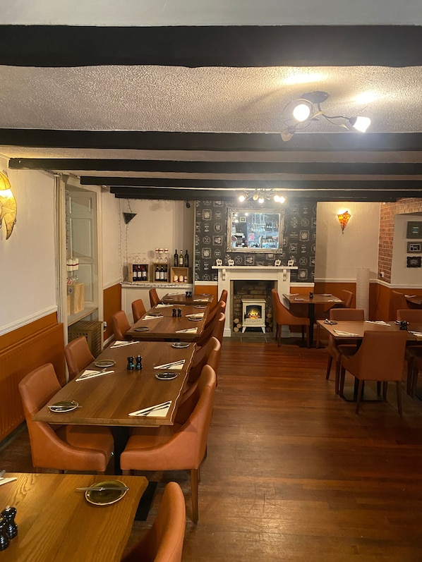 A restaurant with a long wooden table, multiple booths, and a fireplace. - LABURNUM HOUSE & BISTRO EN GLAZE (Wylam)