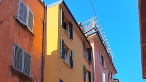 A street with multi-story buildings, some with visible signage, and a clear blue sky. - BuonHotel Bologna Centro (Bologna)