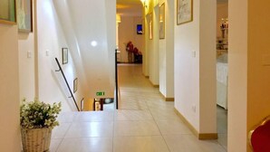 A hotel hallway with a staircase, framed pictures on the walls, and a potted plant. - BuonHotel Bologna Centro (Bologna)