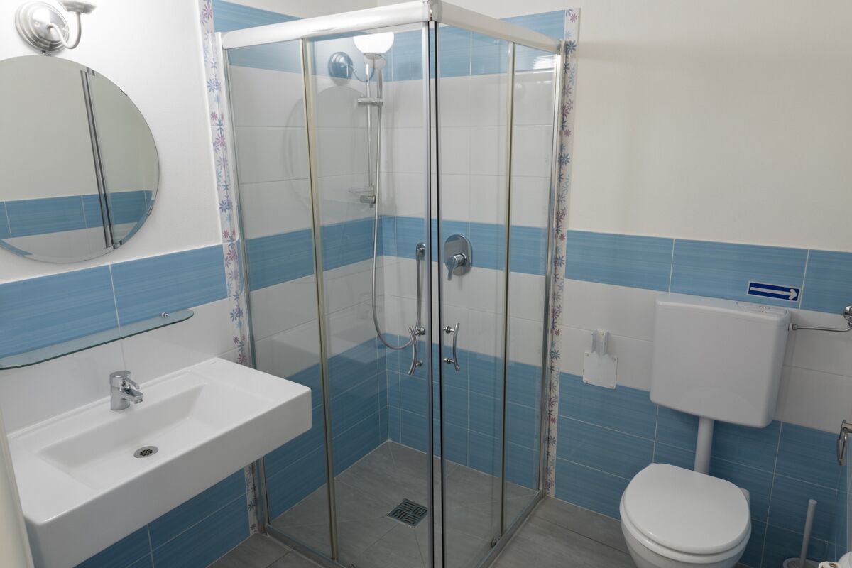 Un baño con ducha envuelta en vidrio, lavamanos, inodoro y espejo.