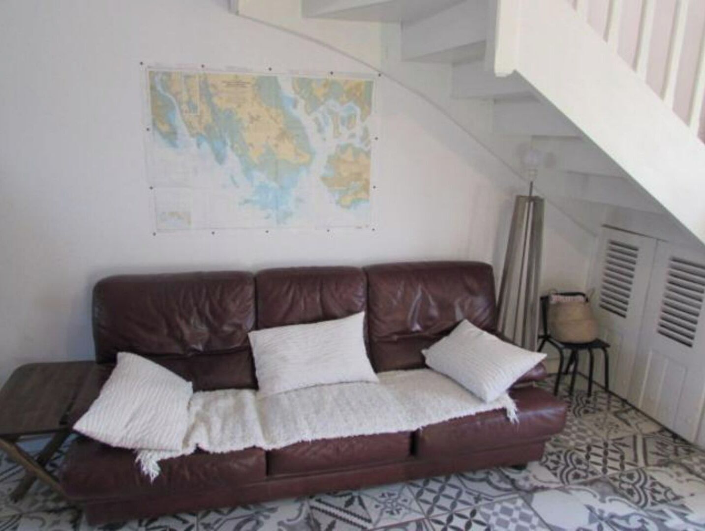 A brown leather sofa with white cushions against a wall with a map.