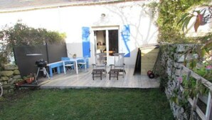 A patio with a wooden deck, a table, and chairs. - Fisherman's cottage (Île-d'Arz)