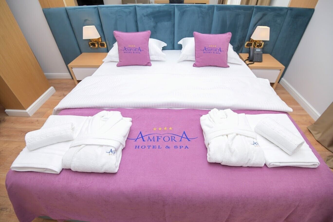 A hotel room with a bed, two pillows, two nightstands, a lamp, and towels.