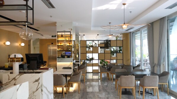 Un hall d’hôtel moderne doté d’un comptoir d’accueil, d’un espace salon et d’une grande fenêtre donnant sur l’extérieur.