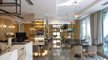 A modern hotel lobby with a reception desk, seating area, and a large window offering a view of the outdoors.