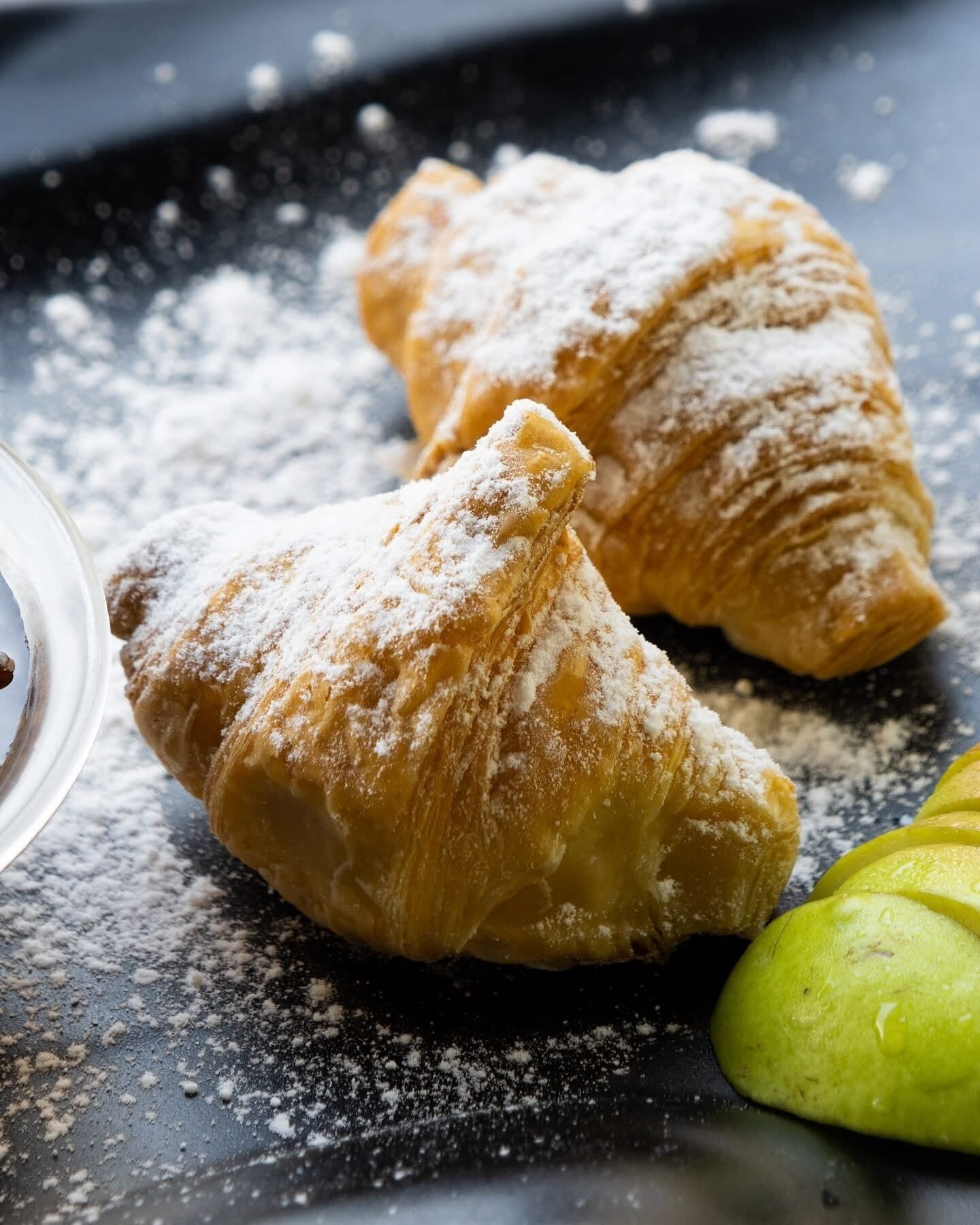 Due dolci spolverati di zucchero a velo su un fondo scuro.