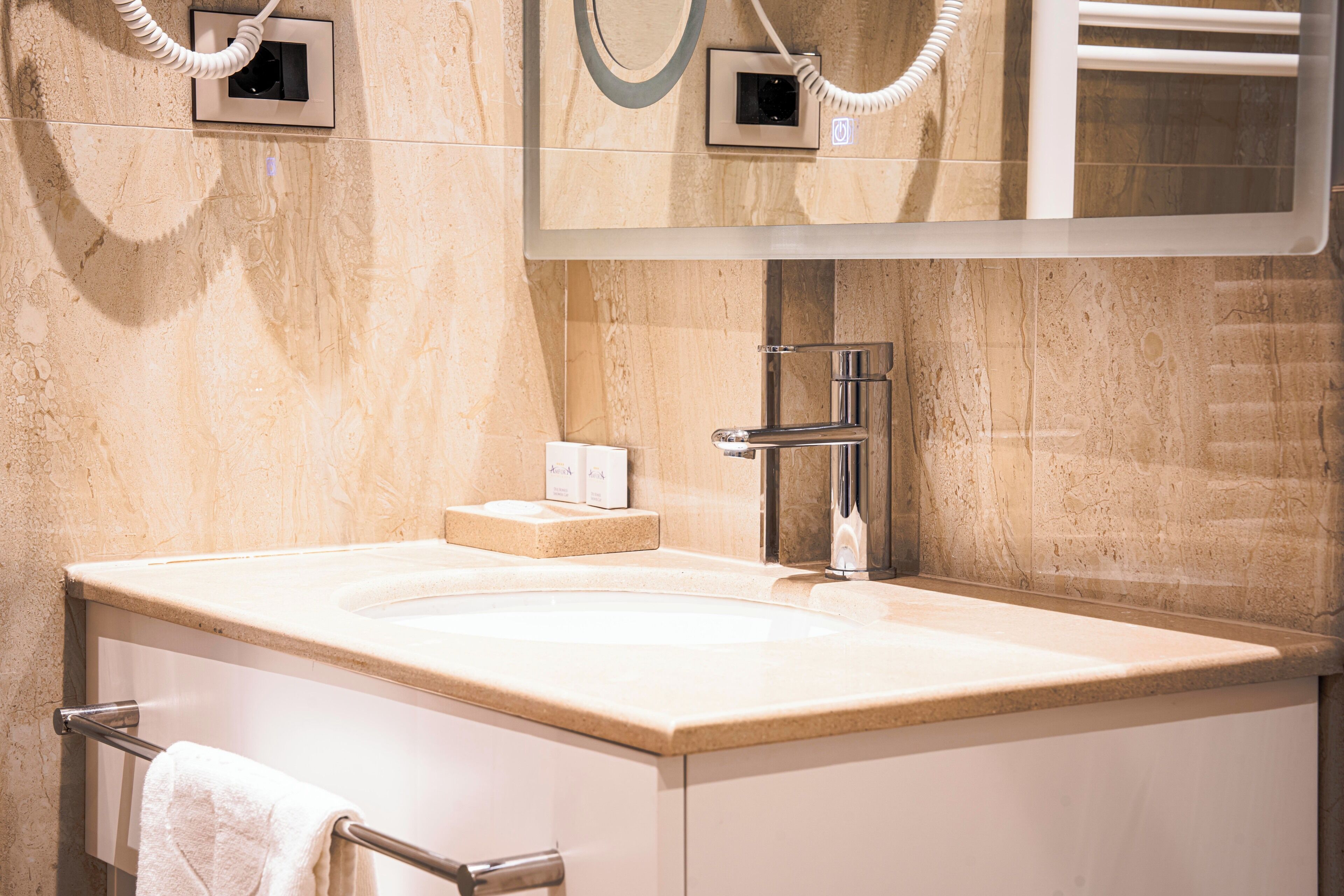 A modern bathroom with a large sink, a mirror, and a towel rack.