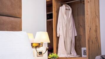Une chambre d’hôtel avec une armoire en bois, une lampe de chevet, un oreiller blanc et un peignoir suspendu à l’intérieur de l’armoire.