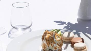 Ein Esstisch mit einer Dessertplatte, einem Glas und einer Vase mit Blumen.