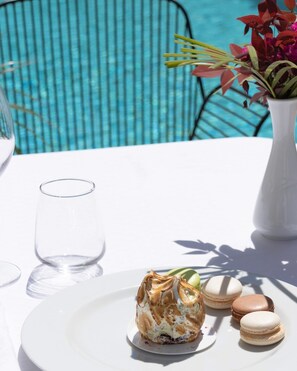 A dining table with a plate of dessert, a glass, and a vase with flowers. - Hotel Amfora (Durrës)