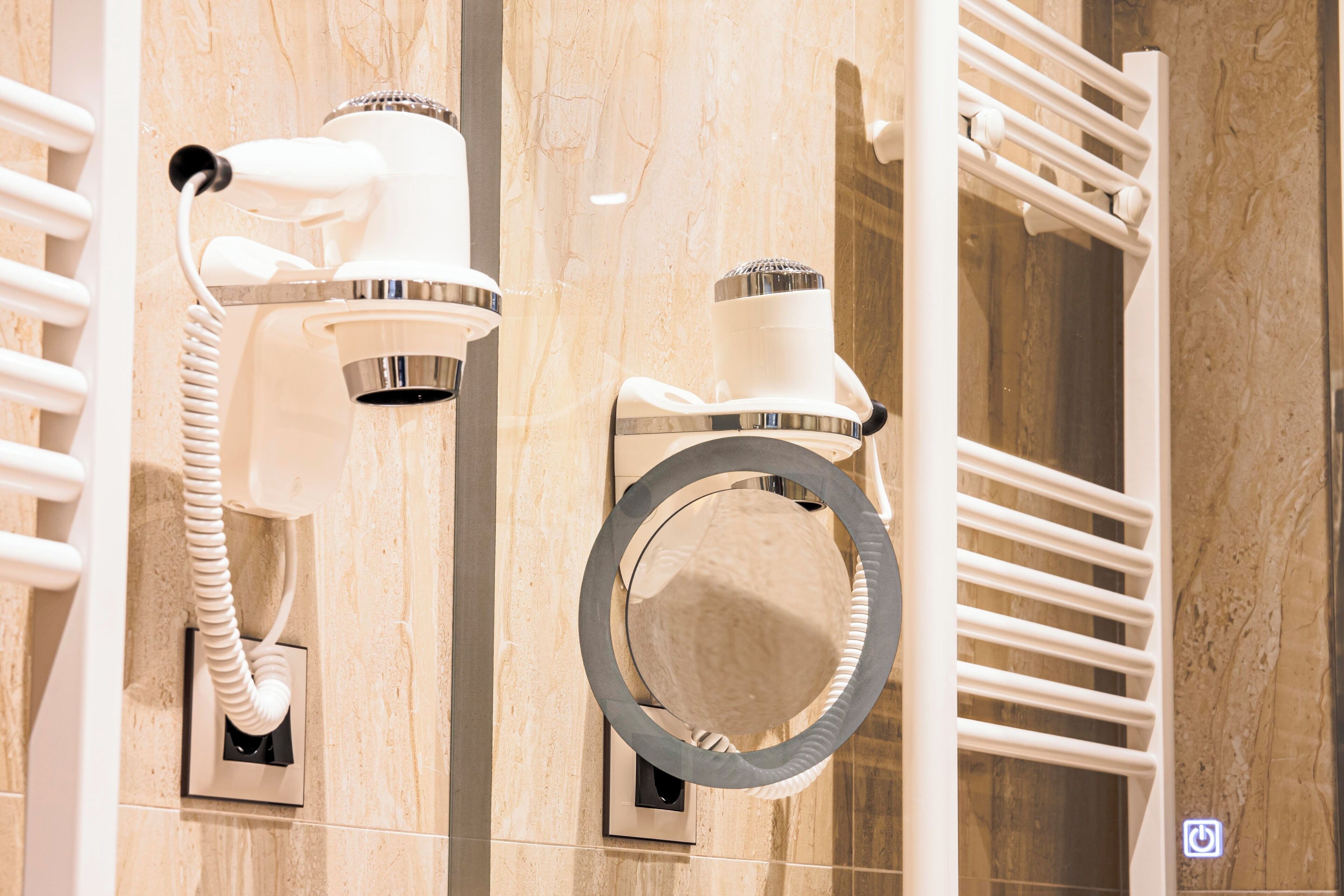 A bathroom with a towel rack, a mirror, and a hairdryer mounted on the wall.