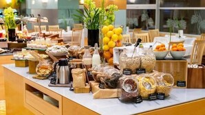 Un buffet proposant une variété d’aliments et de boissons, notamment des fruits, des céréales et du café.