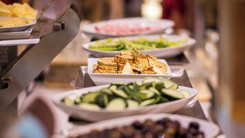 A buffet line with various dishes including salads, fruits, and desserts.