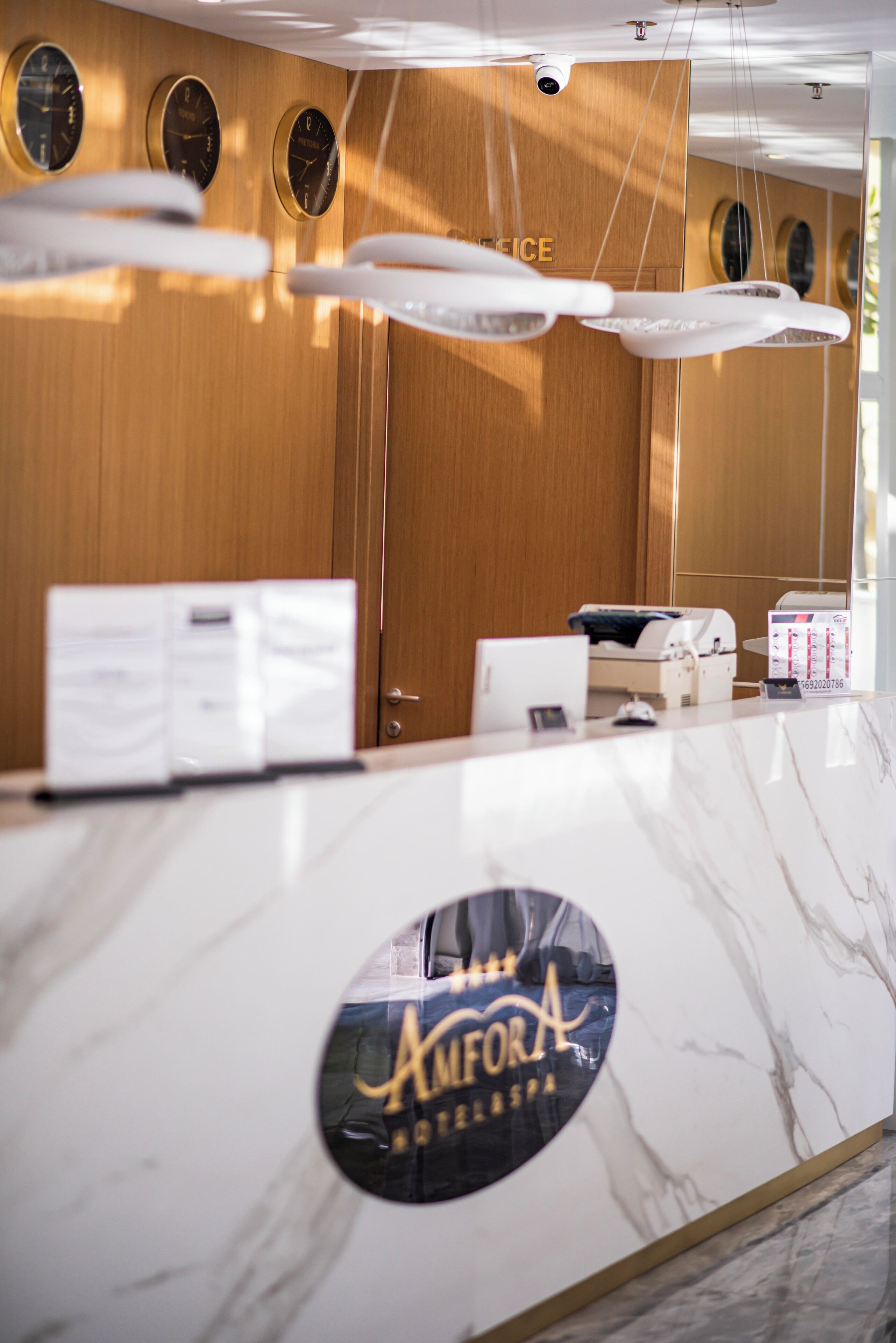 A reception desk with a marble top, a mirror, and a wooden wall with clocks.