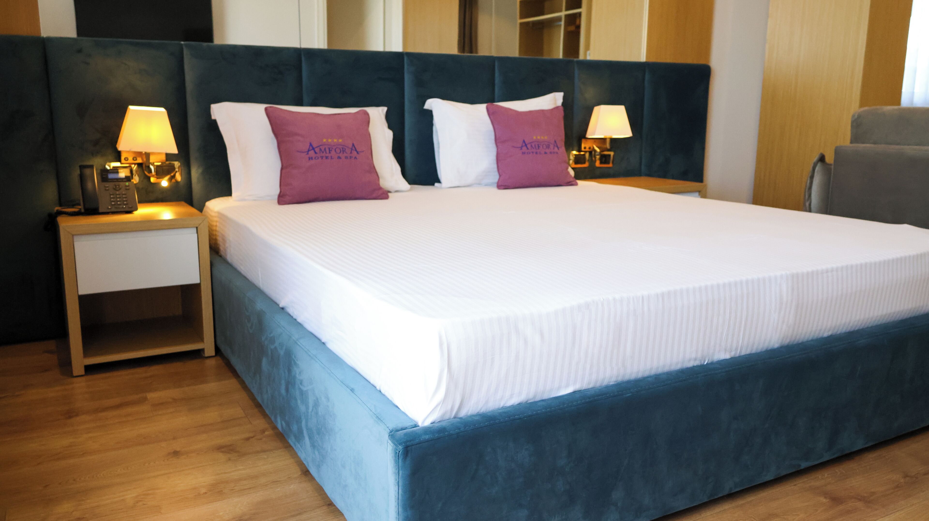 Habitación de hotel con una cama grande, dos mesitas de noche con lámparas y un cabecero.