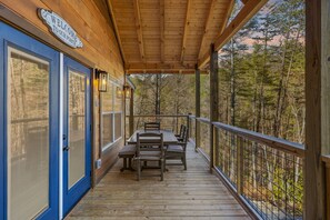 Eine Holzterrasse mit Tisch und Stühlen, eine blaue Tür und ein Schild mit der Aufschrift 'WELCOME TO OUR PORCH'.