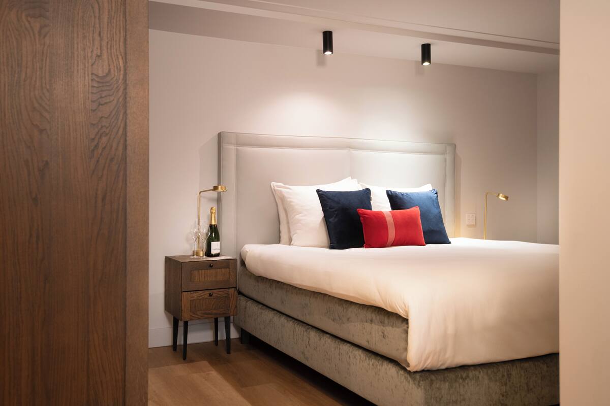 A bedroom with a bed, bedside tables, and a nightstand.