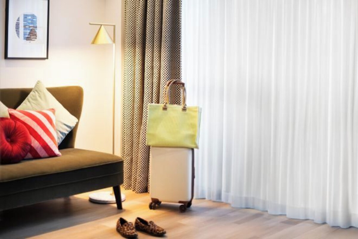 A room with a sofa, a suitcase, and a pair of shoes on the floor.
