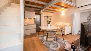 Um interior moderno com uma escada, área de jantar com mesa e cadeiras, um sofá e uma lareira.