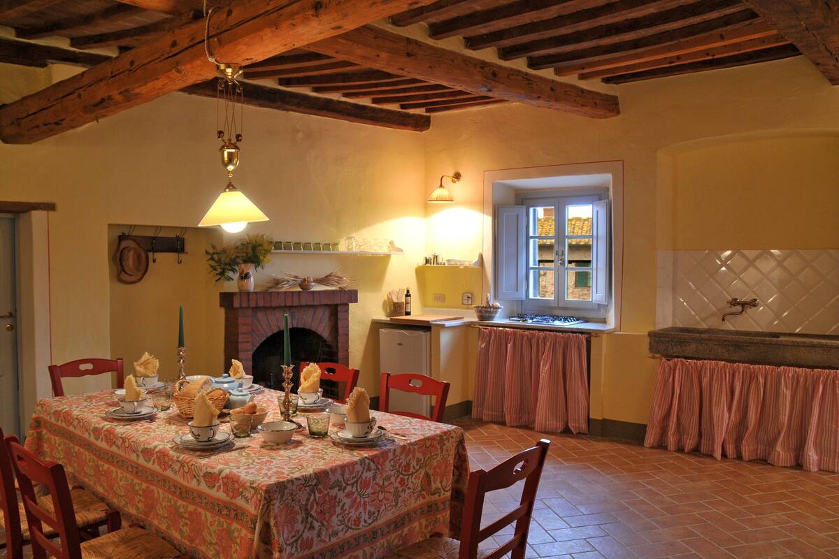 A dining area with a table set for four, a fireplace, and a window with curtains.