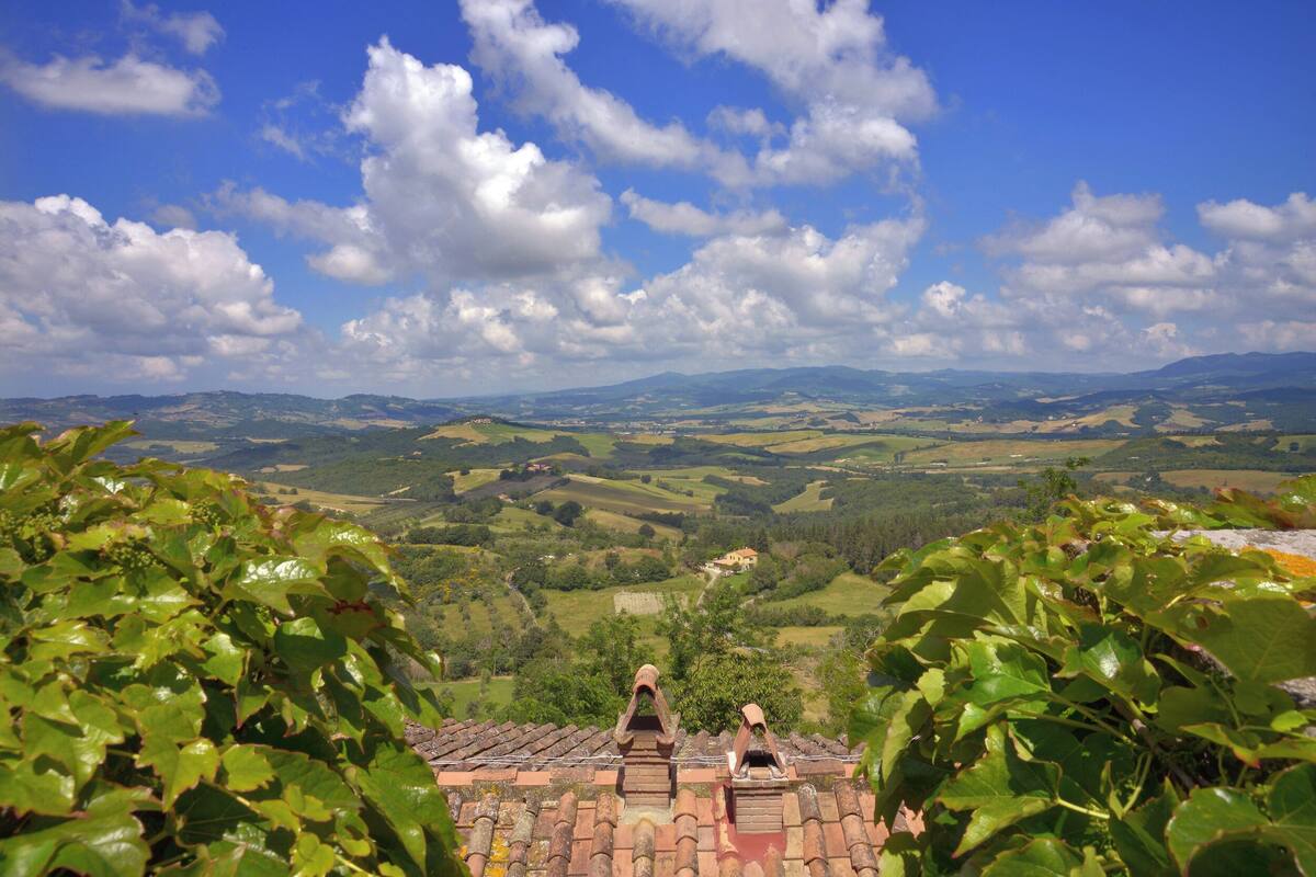 A view from a high vantage point overlooking a valley with terraced fields and a distant house.
