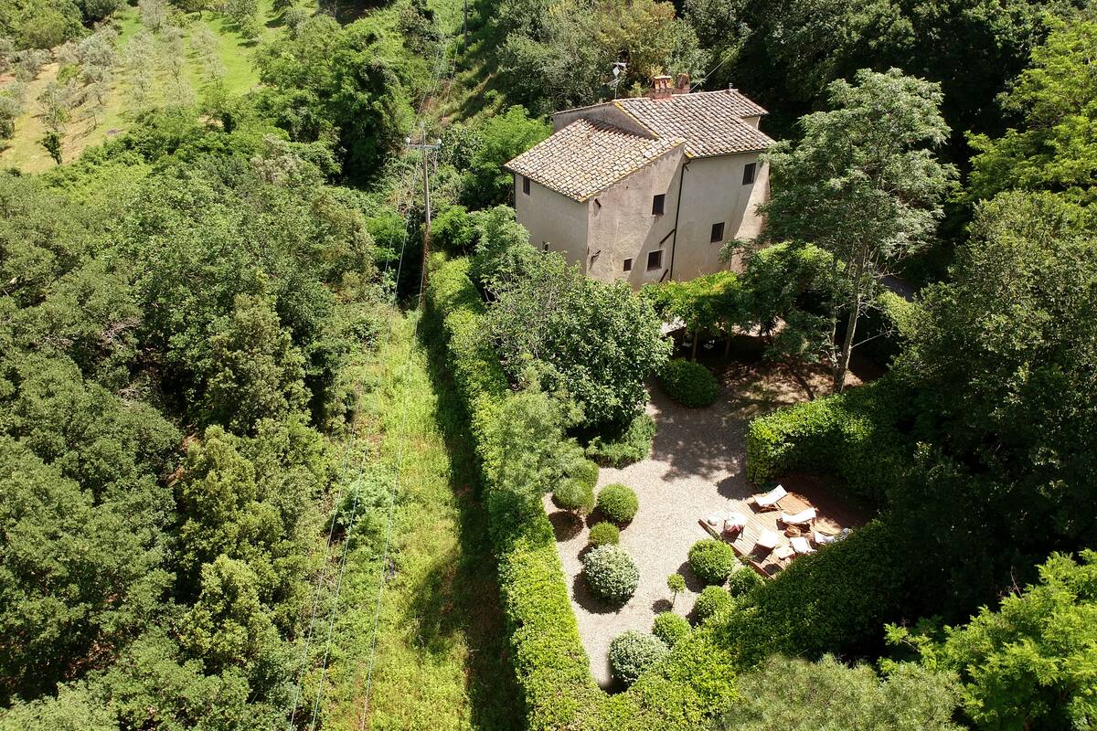 A stone building surrounded by dense greenery, with a small patio area.