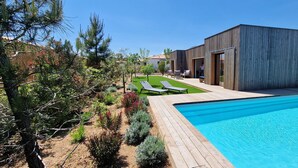 A modern outdoor pool area with a wooden deck, a small lawn, and a building with large windows. - Casa di Leccia, Superb villa close to the beach, private swimming pool (Lecci)