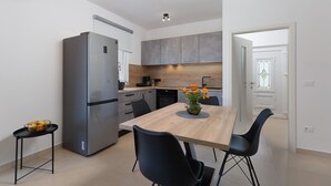 Une cuisine moderne dotée d’un réfrigérateur encastré, d’une table à manger avec des chaises et d’un vase rempli de fleurs.