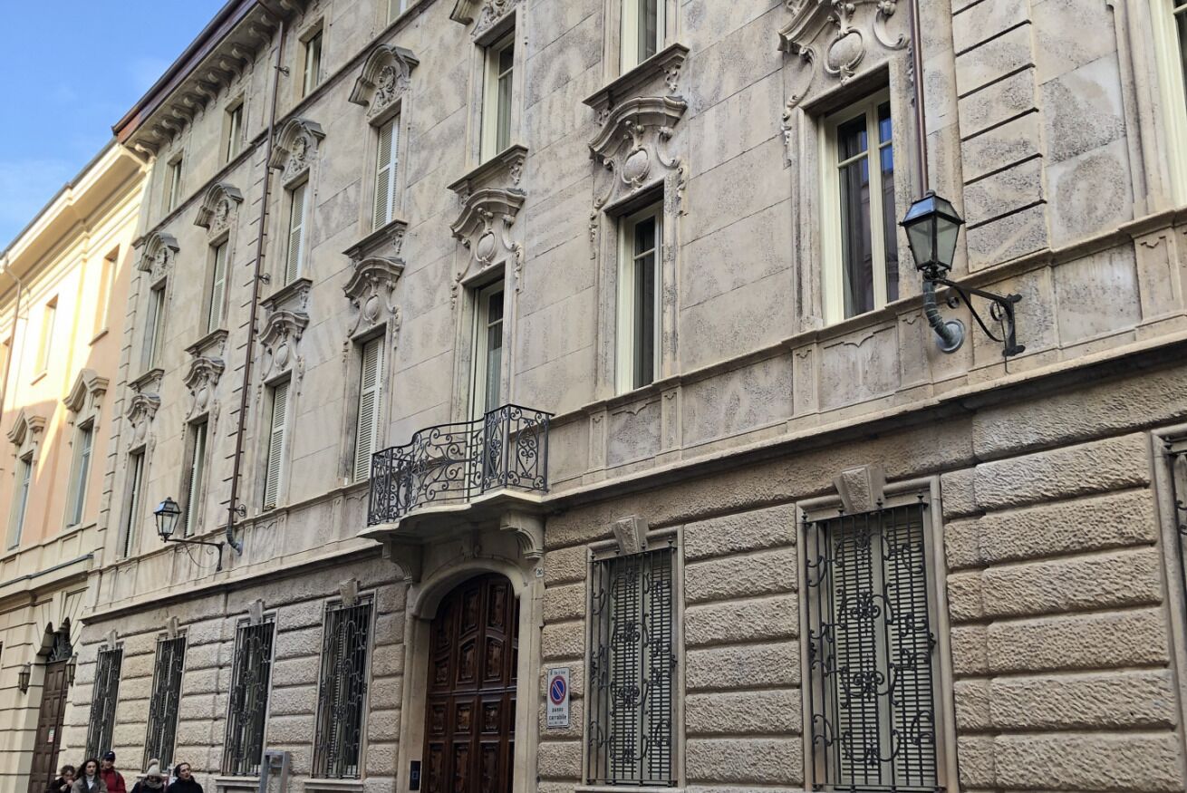 A historic building with ornate architectural details, including a balcony with wrought iron railings and a large wooden door.
